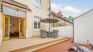 Een terras met tafel, stoelen, een overdekt gedeelte en een loungestoel.
