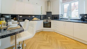 Een moderne keuken met witte kasten, een granieten aanrecht, een ingebouwde oven en een raam met uitzicht.