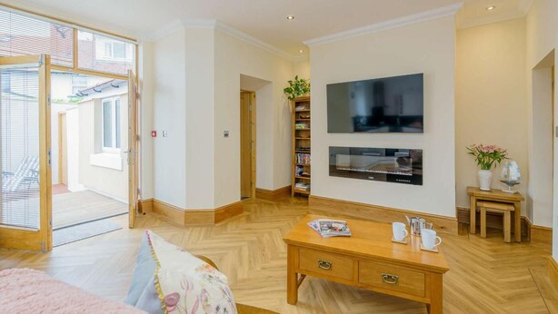 Ruime kamer met houten vloer, een flatscreen televisie aan de muur, een houten bureau met lades en een boekenkast.