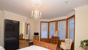 Een slaapkamer met een groot bed, een houten garderobe, een televisie en een kroonluchter.