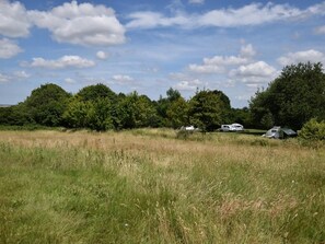 A grassy field with trees and a camping area with RVs. - 2 Bed in Taunton (oc-83696) (Thornfalcon)