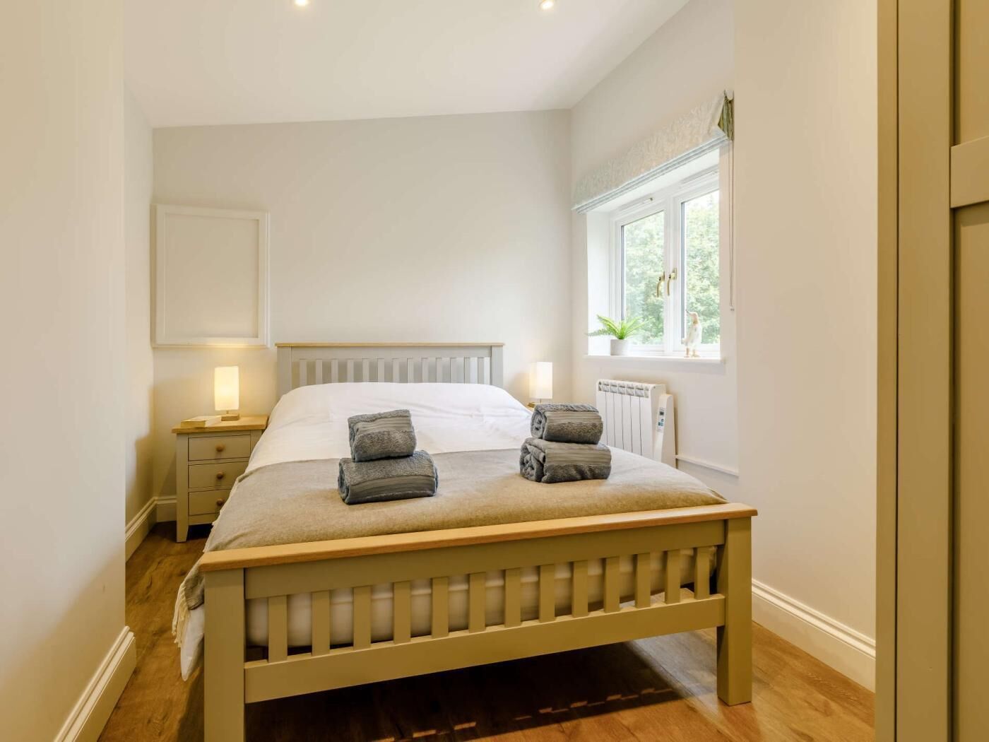 A bedroom with a bed, bedside tables, a window, and a radiator.