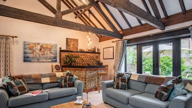 Ein gemütliches Wohnzimmer mit zwei grauen Sofas, einem Holztisch und einem Kamin aus Ziegelsteinen.