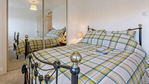 A bedroom with a bed, a mirror, a lamp, and a wardrobe. - 3 Bed in Crewkerne (oc-83943) (Haselbury Plucknett)
