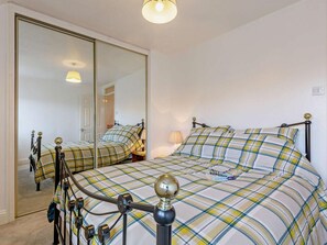 A bedroom with a bed, a mirror, a lamp, and a wardrobe. - 3 Bed in Crewkerne (oc-83943) (Haselbury Plucknett)