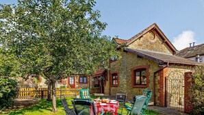 A stone house with a garden, outdoor seating, and a wooden fence. - 3 Bed in Crewkerne (oc-83943) (Haselbury Plucknett)