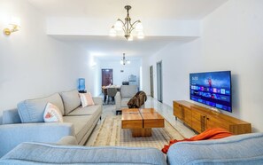 Uma sala de estar com sofá, mesa de centro, televisão e dispensador de água.
