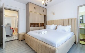 Et hotelværelse med seng, garderobeskab, natbord og et badeværelse, der kan ses gennem en åben dør.