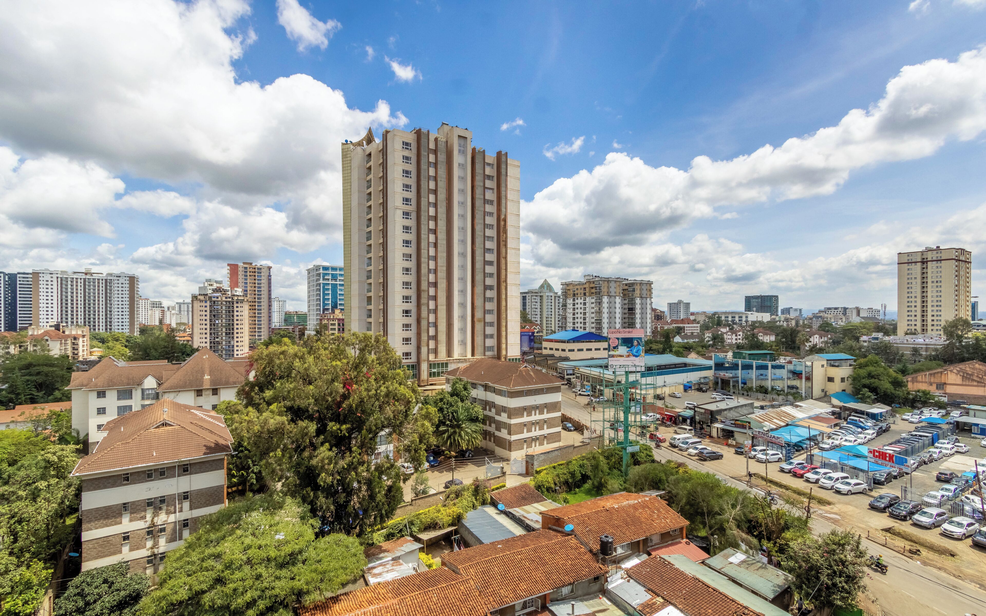 A cityscape with high-rise buildings, a parking lot, and a mix of residential and commercial structures.