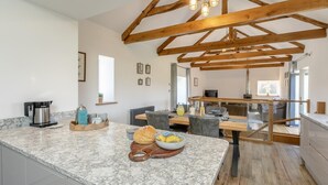 Uma cozinha com bancadas de mármore, vigas de madeira e uma área de jantar com mesa e cadeiras.
