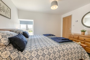 Ein Schlafzimmer mit einem Bett, einem Schminktisch, einem Spiegel und einem Fenster mit Blick.