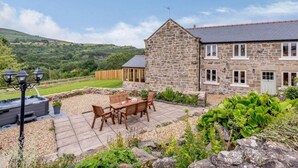A stone house with a patio, outdoor seating, and a view of the countryside. - 3 Bed in Wrexham (oc-83938) (Coedpoeth)