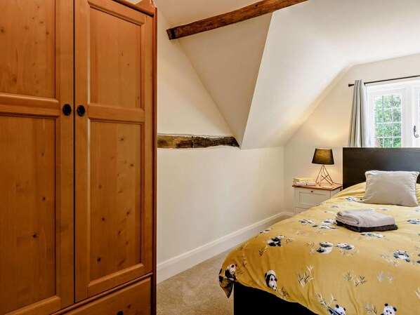 A bedroom with a bed, a nightstand, a lamp, and a wardrobe.