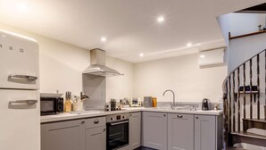 A modern kitchen with grey cabinets, a built-in oven, a microwave, and a stainless steel range hood. - 1 Bed in Frome (oc-83834) (Holwell)