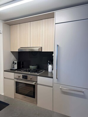 Eine moderne Küche mit Edelstahlgeräten, hellen Holzschränken und einem eingebauten Backofen.