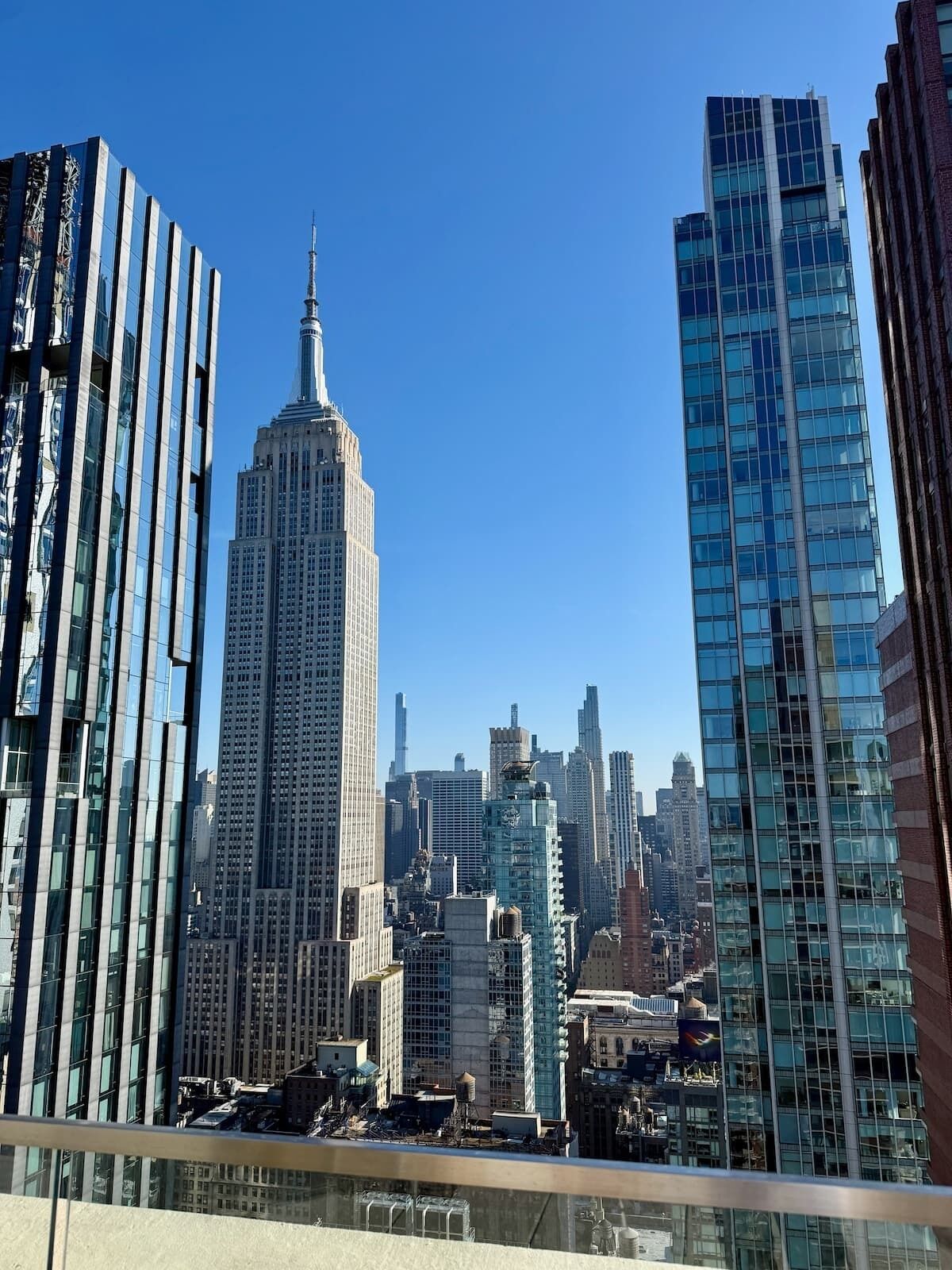 Un paysage urbain avec des immeubles modernes de grande hauteur, dont un gratte-ciel remarquable surmonté d’une flèche.