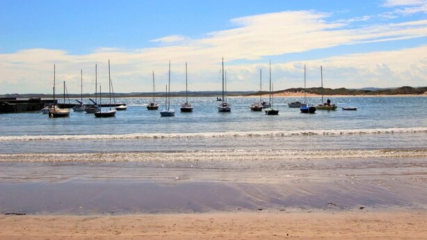Une plage où des bateaux sont amarrés dans l’eau.