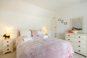 A bedroom with a bed, two bedside tables, a dresser, a mirror, and a wall with framed pictures. - 2 Bed in Bideford (oc-83808) (Weare Giffard)