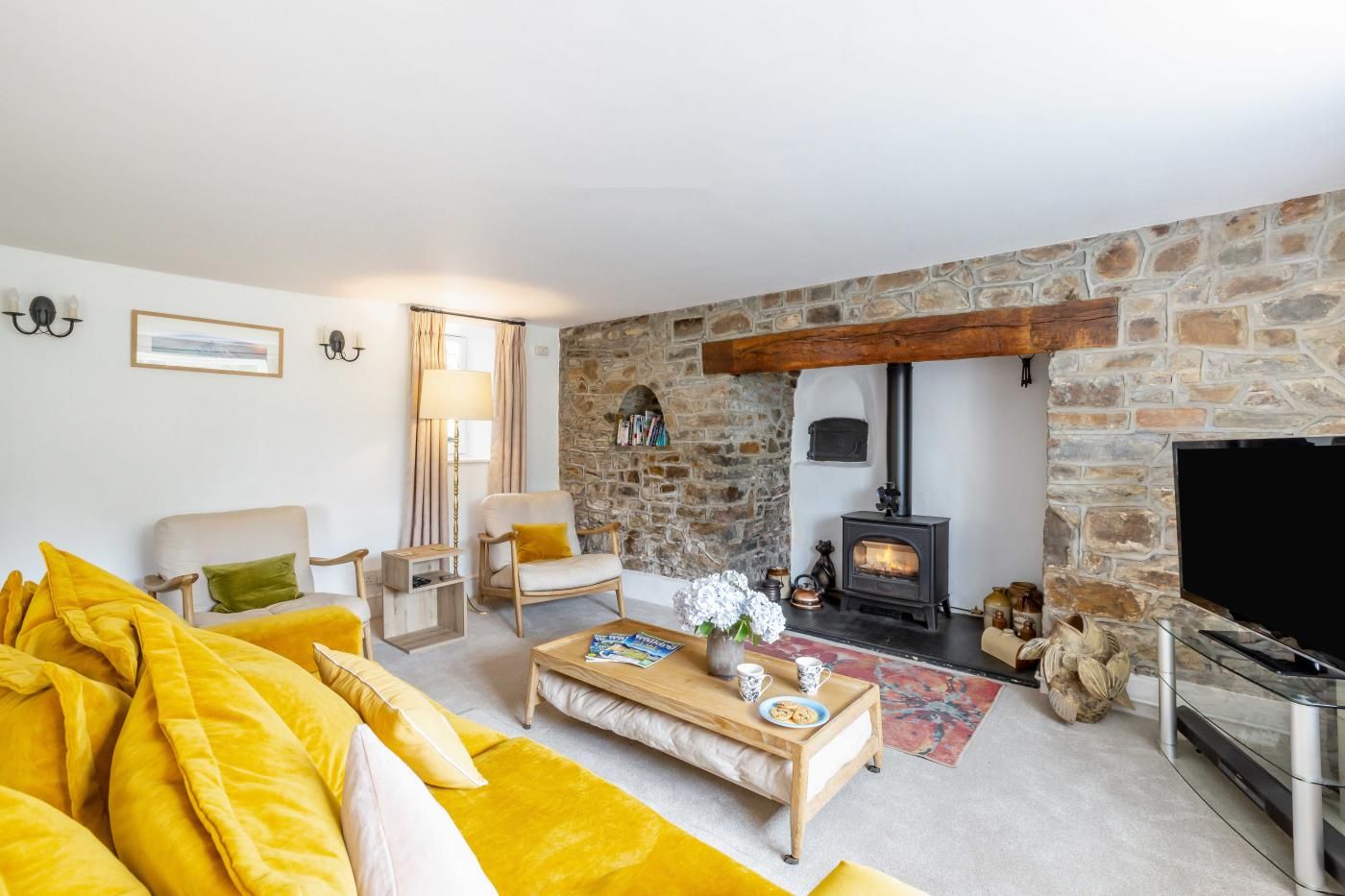 Ein Wohnzimmer mit Kamin aus Stein, einer Couch, einem Couchtisch und einem Fernseher.