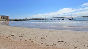 A beach with boats, a sandy shore, and a building in the background. - 4 Bed in Chathill (oc-83469) (Swinhoe)