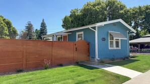 Une petite maison bleue avec une clôture en bois, une seule porte et un petit porche.