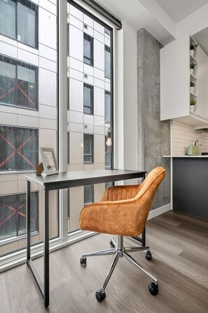 A modern office space with a desk, swivel chair, and large windows.