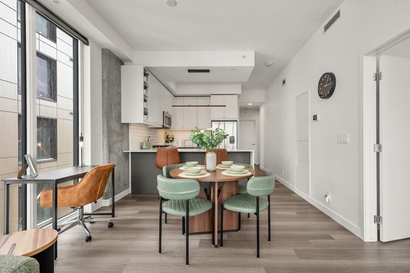 A modern kitchen with white cabinets, a central island, and a dining area with a round table and four chairs.