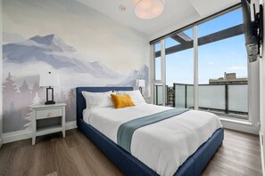 Ein Schlafzimmer mit Bett, Nachttischen, einem Fenster mit Blick und einem Wandgemälde.
