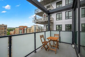 A balcony with a table and chairs, a view of the cityscape, and a building with balconies. - The Summit | Sofa Bed | UG Prk | AC | Min to Stmp (Calgary)