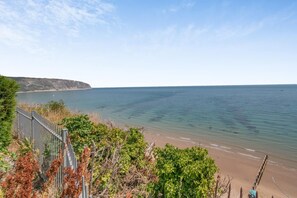 A coastal landscape with a clear view of the sea, a sandy beach, and a rocky cliff. - 3 Bed in Swanage (oc-83794) (Swanage)