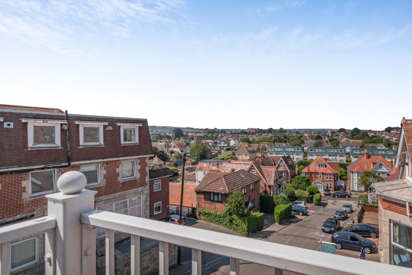 A residential area with houses, a clear sky, and a balcony with a white balustrade.