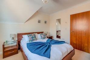 A bedroom with a bed, bedside tables, a mirror, and a wooden door. - 3 Bed in Swanage (oc-83794) (Swanage)