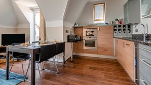 Een moderne keuken met een eethoek, inbouwapparatuur en een groot raam.