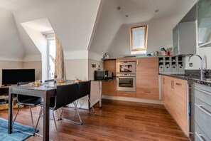 A modern kitchen with a dining area, built-in appliances, and a large window. - 3 Bed in Swanage (oc-83794) (Swanage)