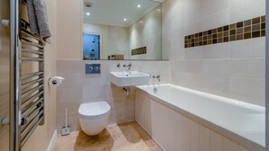 Een moderne badkamer met toilet, wastafel en bad.
