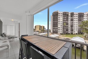 A balcony with a table and chairs, overlooking a high-rise building and a body of water. - Casa Marina Condo with amenities (Fort Myers Beach)