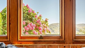 Une fenêtre donnant sur des fleurs roses et un paysage.