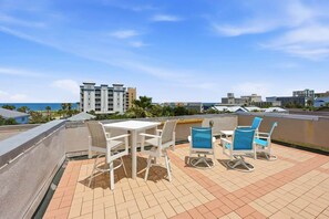 Une terrasse sur le toit, avec une table et des chaises, offrant une vue sur le paysage urbain de la côte.