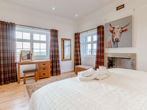 Ein Schlafzimmer mit Bett, Schreibtisch, Stuhl, Spiegel und Kamin.