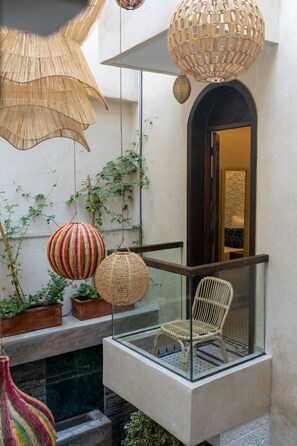 A balcony with wicker furniture, hanging lamps, and potted plants. - Riad Secret Mahjouba (Marrakech)