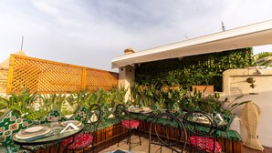 An outdoor dining area with a round table and chairs, surrounded by lush greenery and a wooden fence. - Riad Secret Mahjouba (Marrakech)