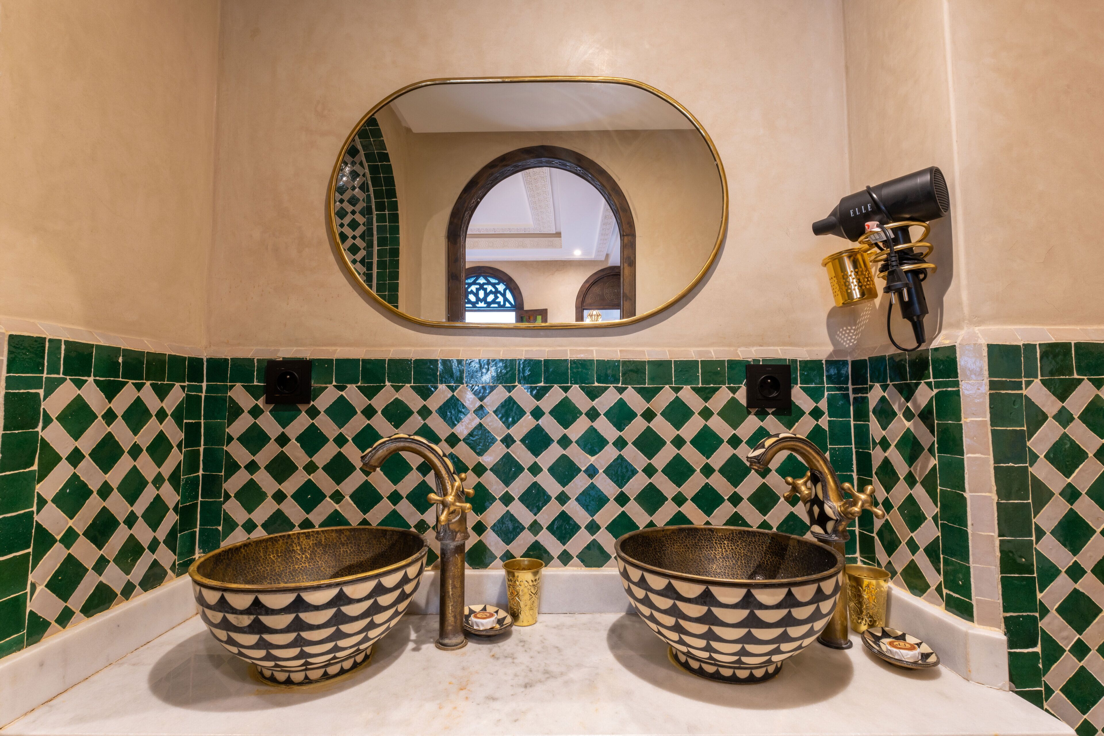 A bathroom with two large decorative bowls as sinks, a mirror, and a hairdryer mounted on the wall.