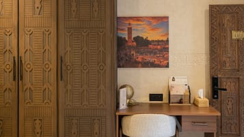 Una habitación con escritorio, silla y un amplio armario de madera con detalles tallados.