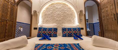 A room with a bed, pillows, a rug, and a decorative wall.