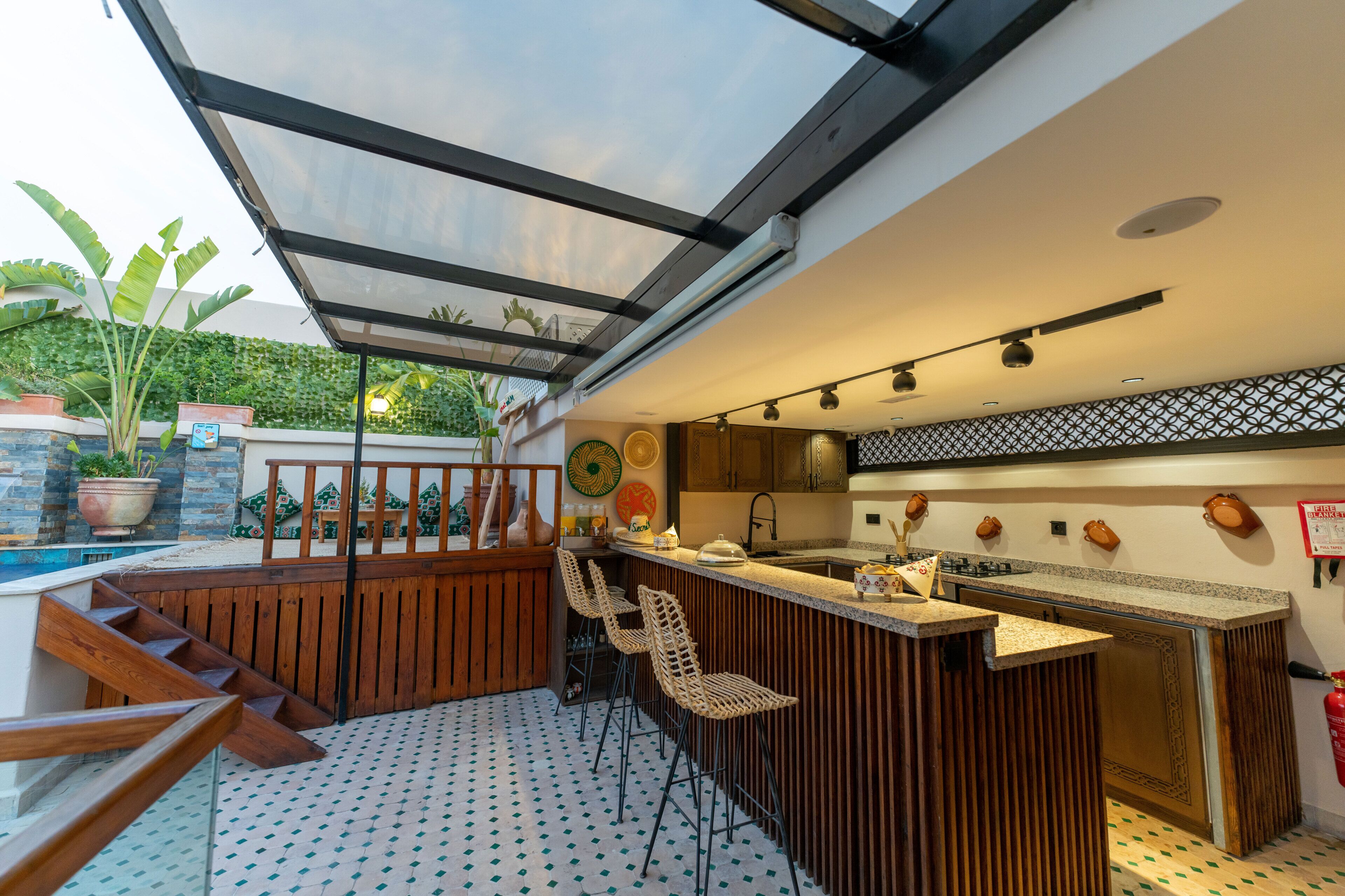 Una cocina moderna con barra, un comedor con banco de madera y vista a una piscina.