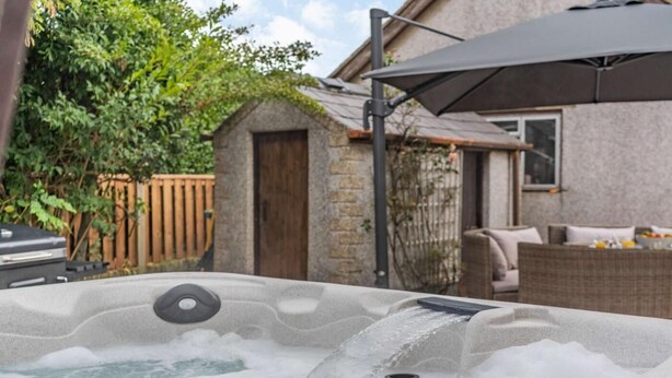 A hot tub with a control panel, surrounded by outdoor furniture and a wooden fence. - 3 Bed in Poulton-le-fylde (oc-83787) (Hambleton)