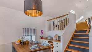 A modern kitchen with a wooden island, white cabinets, and a staircase with wooden steps. - 2 Bed in Cardigan (oc-83919) (Cilgerran)