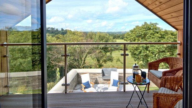 A balcony with wicker furniture, a coffee table, and a view of a green landscape. - 2 Bed in Cardigan (oc-83919) (Cilgerran)