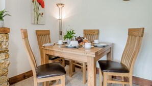 A dining area with a wooden table, four chairs, a clock, and a painting on the wall. - 2 Bed in Bridport (oc-58848) (Powerstock)