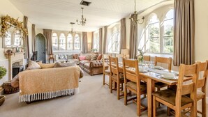 Un espacio amplio con comedor, chimenea y ventanas grandes.